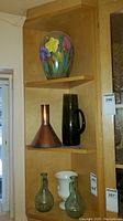 Three-shelf view showing hand-painted vase on top, copper funnel and olive-green glass vase on middle shelf