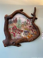 Full view of the framed wall art showing the textured wooden frame and colorful pressed flower design.