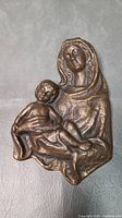 Full view of the bronze Madonna and Child wall plaque showing the detailed relief.