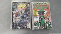 Two stacks of comic books showing front covers of Justice League and Green Lantern annual titles.
