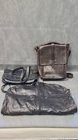 Three bags displayed together showing all items in the lot, including the garment bag, leather satchel, and purse.