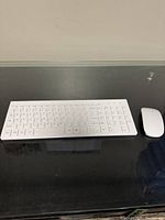 White Bluetooth keyboard and mouse set placed on a black surface, clean and intact condition.