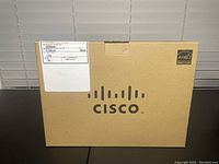 Closed brown original packaging box with Cisco branding and shipping label visible.