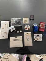 Lot of assorted earrings, two small necklaces and two watches arranged on a table
