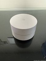 Top view of the Google Home WiFi router showing circular white design and G logo on top.