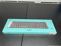 Sealed Logitech K230 keyboard in turquoise box with product image and branding visible.