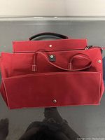 Photo showing the red Maxx bag with an open top flap and visible front snap pocket and handles.