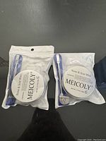 Front view of two sealed packages of Meicoly Nose & Scar Wax, each with a blue-handled scalpel inside the clear plastic packaging.