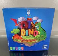 Box front view showing product name, age recommendation 3+, and colorful dinosaur cartoon graphics on a blue background.