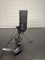 Front view of black FIFine USB microphone mounted on tripod stand with visible USB cable and microphone mute button.