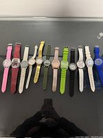 Ten assorted wrist watches laid out in a row showing straps and faces