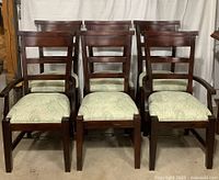 Front view of all 6 dining chairs arranged in two rows, showing wood finish and cushioned seats with paisley fabric.