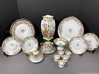 Full set display showing three styles of hand-painted Nippon porcelain table decor including vases, plates, bowls, sugar pot, compotes with floral and gold detail.