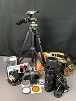Full lot arrangement showing camera body, lenses, tripod, filters, film, manual, carry bag