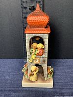 Front view of the porcelain figurine showing children inside the tower and below