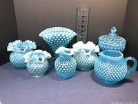 Front view of all seven blue opalescent hobnail glass pieces with ruler