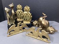 All eight brass items displayed together showing the pineapple bookends, Spread Eagles, and four cat figurines in two styles and poses.