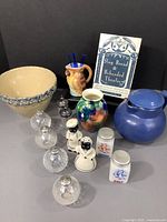 Overview of the collection including Roseville mixing bowl, stoneware carafe, ceramic vase and parrot pitcher, salt & pepper shakers, kitchen chef figurines, glass sets, and book