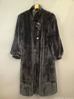 Full view of the vintage floor-length dark brown mink coat hanging with visible button front closure and puffed sleeves.