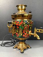 Full view of the samovar showing gold tone with floral and strawberry painted pattern, power cord and ornate spout.