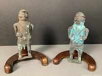 Front view of the pair of Yoruba metal sculptures depicting a man and woman with visible mineral deposits and green patina.