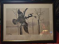 Framed sepia-toned print showing three ducks in flight over bare trees, signed by Donald Douglass and numbered as a limited edition piece.