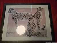 Photo of framed cheetah print showing both cheetahs in front and side profile with pink beige background.