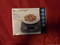 View of the AccuWeight digital kitchen scale box showing almonds on a plate on the scale.