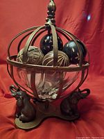 Full view of the decorative centerpiece showing metal orb cage, glass bowl inside, and elephant figure base.