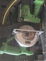Photo showing a green Skil jig saw, a small Skil circular saw with metal blade guard, and a strip of nail fasteners inside a black hard case.