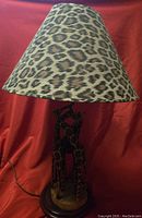 Full lamp with animal print shade and giraffe base on red background