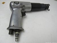 Full view of pneumatic air chisel showing its size and metal body with some marks and scratches.