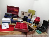 Full view of box contents showing variety of ring boxes in different materials and colors including red velvet, navy blue, beige, black, and wooden trays.