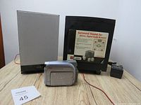 Photo showing Labtec LCS-2514 subwoofer, Sony SS-CEH15 speaker, Canon ZR500 Mini DV camcorder, and a power adapter on wooden table.