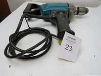 Right side view of Makita drill mixer showing spade handle, metal chuck, and power cord coiled beside it.