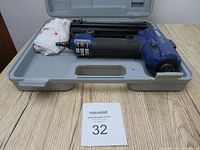 Blue Rona 2 inch, 18 gauge brad nailer inside a molded grey carrying case on a wood surface