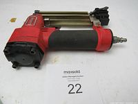 Front side view of the Samona pneumatic pinner showing red body, black grip, and metal pin cartridge.