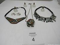 Full lot arranged on white background showing all vintage jewelry items including necklaces, pendant, earrings, and glass bottle pendants.