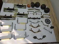 Full lot of 30 vintage drawer pulls and knobs in various materials and styles laid out on white surface.
