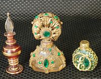 Front view of three ornate perfume bottles on a dark textured surface