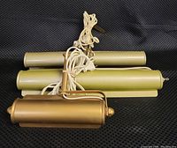 Three gold tone overhead art lamps stacked for size comparison, two large and one smaller lamp with cords attached.