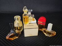 Six small vintage miniature perfume bottles displayed on black fabric, showing all bottles together for identification and condition assessment.