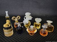 Front view of all nine mini perfume bottles arranged on black fabric with textured pattern