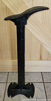 Front view of the antique cast iron shoe last stand showing the top platform and vertical support.