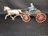 Side view of entire toy set showing white horse, black fire wagon with red wheels, and seated rider in blue.