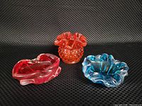 All three glass pieces together: amberina hobnail ruffle top vase in center with red and aqua blue ashtrays flanking it