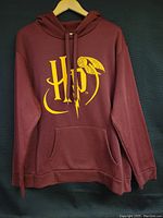 Front view of the burgundy hoodie showing the HP logo and golden snitch graphic