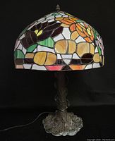 Full view of the stained glass lamp showing the floral design on the shade and metal base with paint loss.