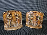 Front view of both bronze bookends showing raised relief of man and woman in farming scene.
