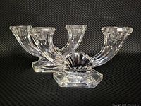 Pair of Val St. Lambert crystal double branch flame candlestick holders side by side against a black background showcasing shape and condition.